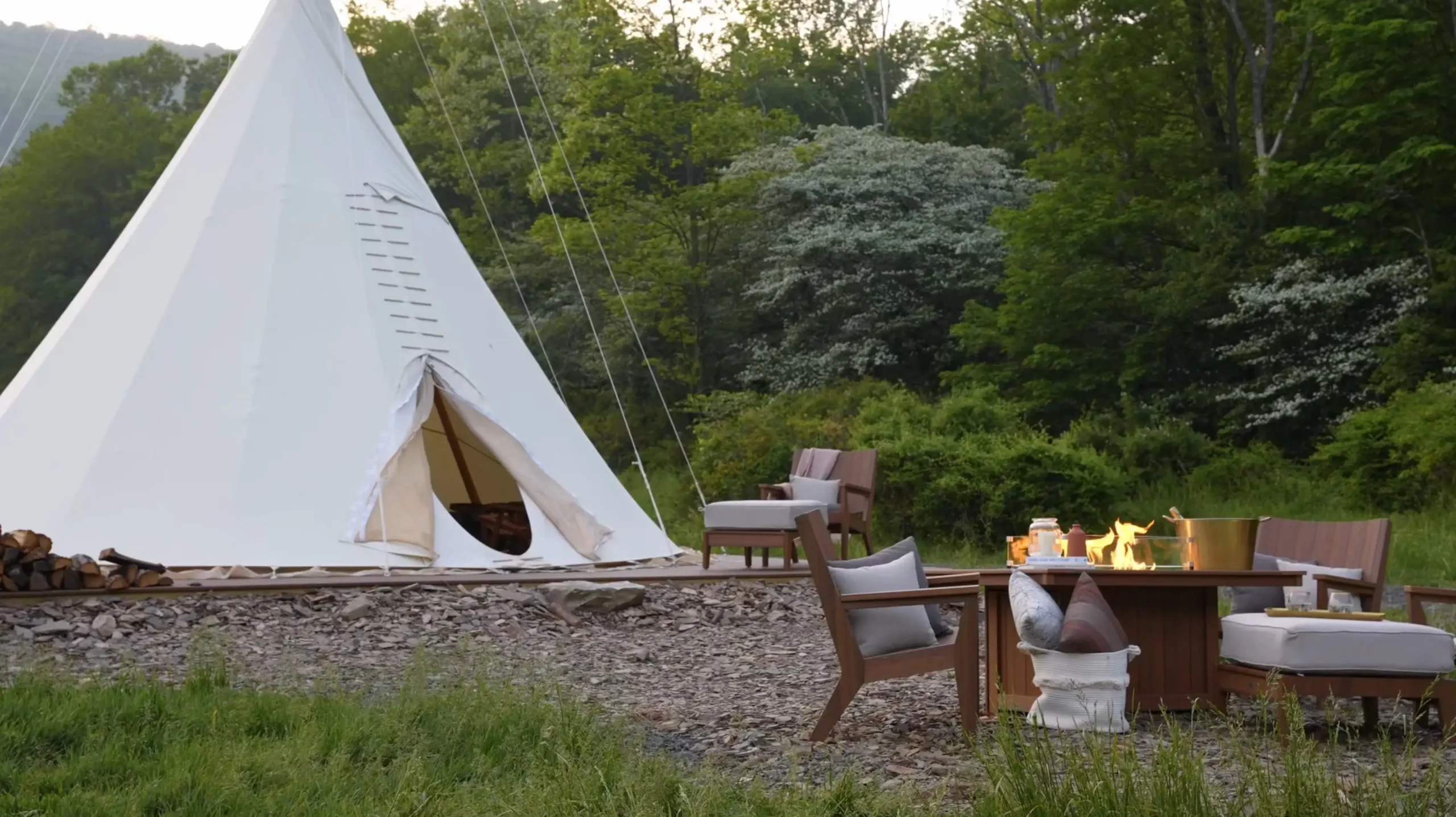 Outdoor chair, fire pit in front of a teepee in a camping setting