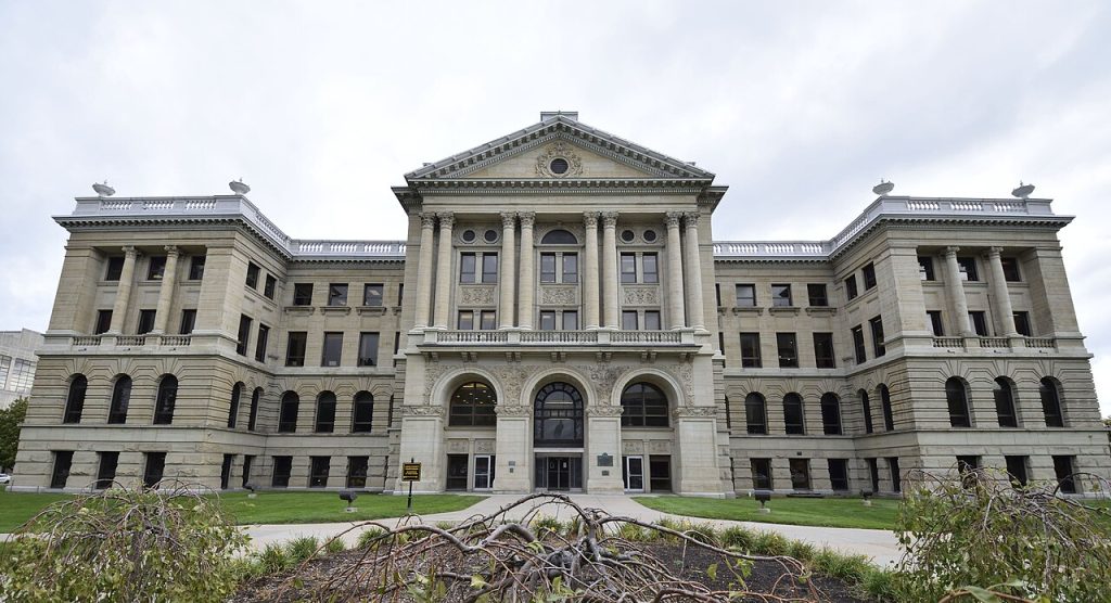 Lucas County Courthouse, a Beaux-Arts style sandstone building in Toledo, Ohio, with classical columns, symmetrical design, and ornate architectural details. Millwest supplies furniture to all of Lucas County.
