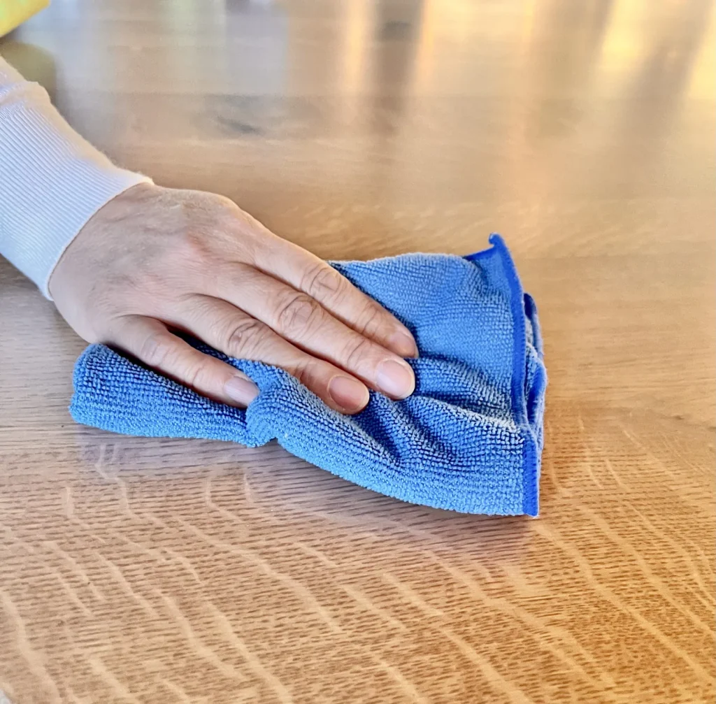Hand wiping wood surface with micro fiber towel