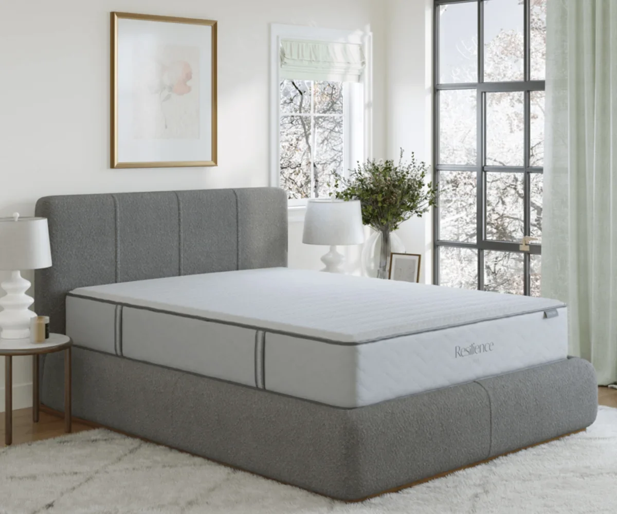 Amish Resilience collection mattress on a gray upholstered foundation, styled in a bright sunlit bedroom.