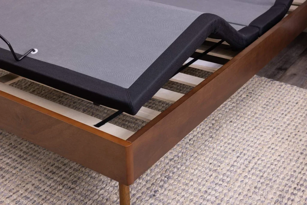 Amish Motion Bases collection, an adjustable power bed base raised at the head on a wooden platform frame over a woven rug.