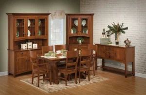 Amish Sara Ann dining collection in oak, shown in a green-walled room with a table, chairs, corner hutches, and a sideboard.