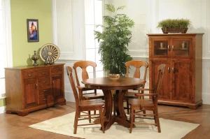 Amish Porter dining collection in cherry, staged with a round pedestal table, chairs, buffet, and cabinet.