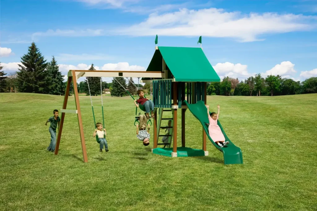 Amish wooden swing set with a green wave slide, two swings, trapeze rings, and a green-roofed fort with children playing